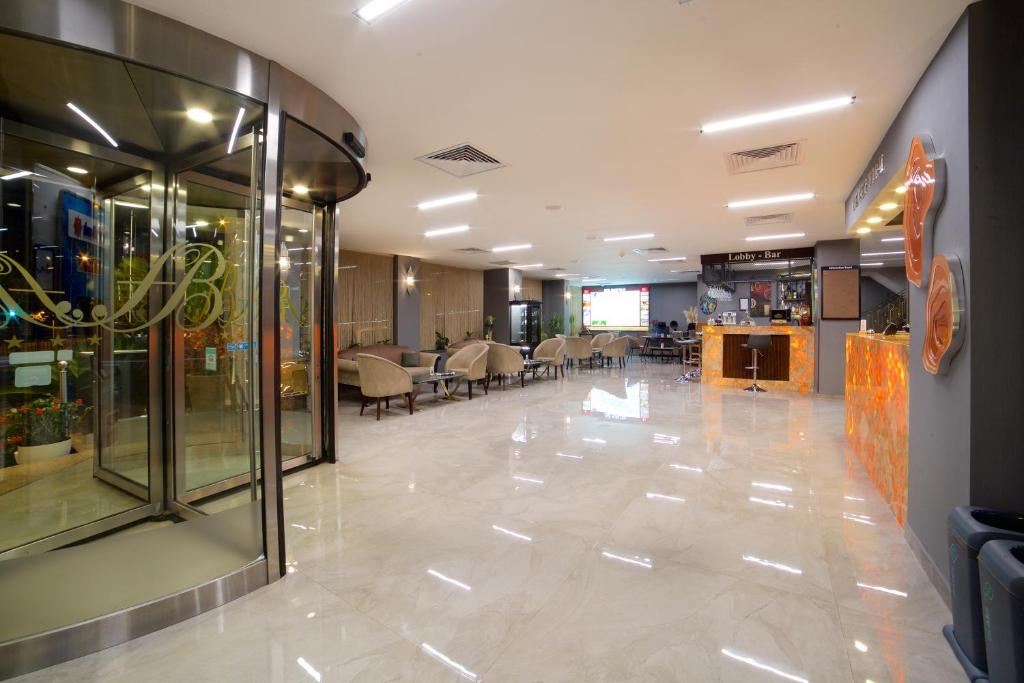 Hotel Bulvar Palas - a large lobby with a waiting area with tables and chairs at Hotel Bulvar Palas in Istanbul