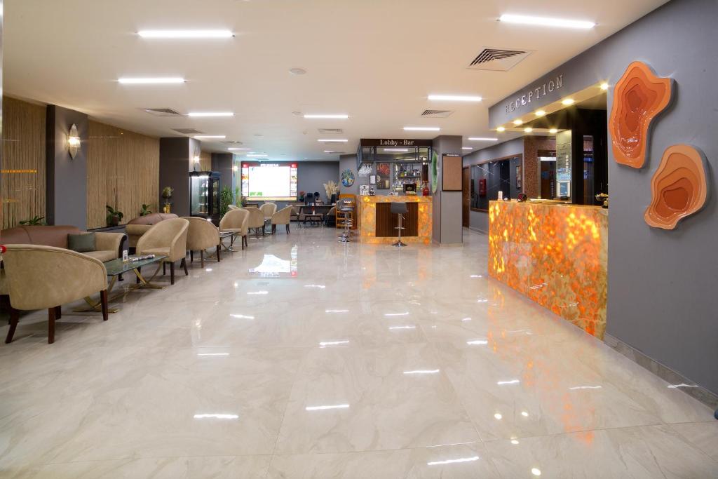 Hotel Bulvar Palas - a lobby with a waiting area with chairs and tables at Hotel Bulvar Palas in Istanbul
