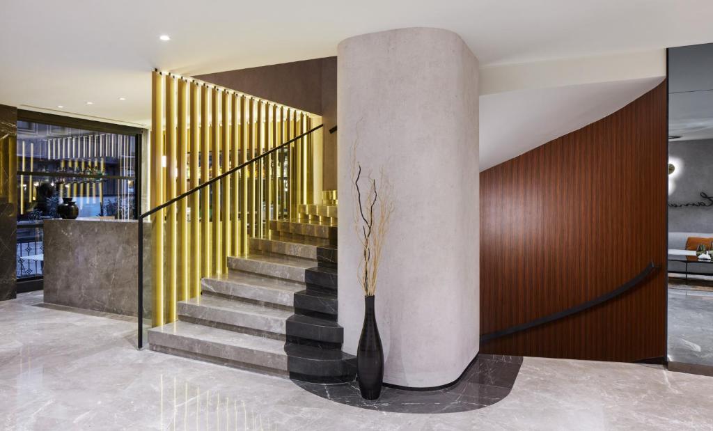 Lamartine Hotel - a lobby with a staircase and a column with a vase at Lamartine Hotel in Istanbul