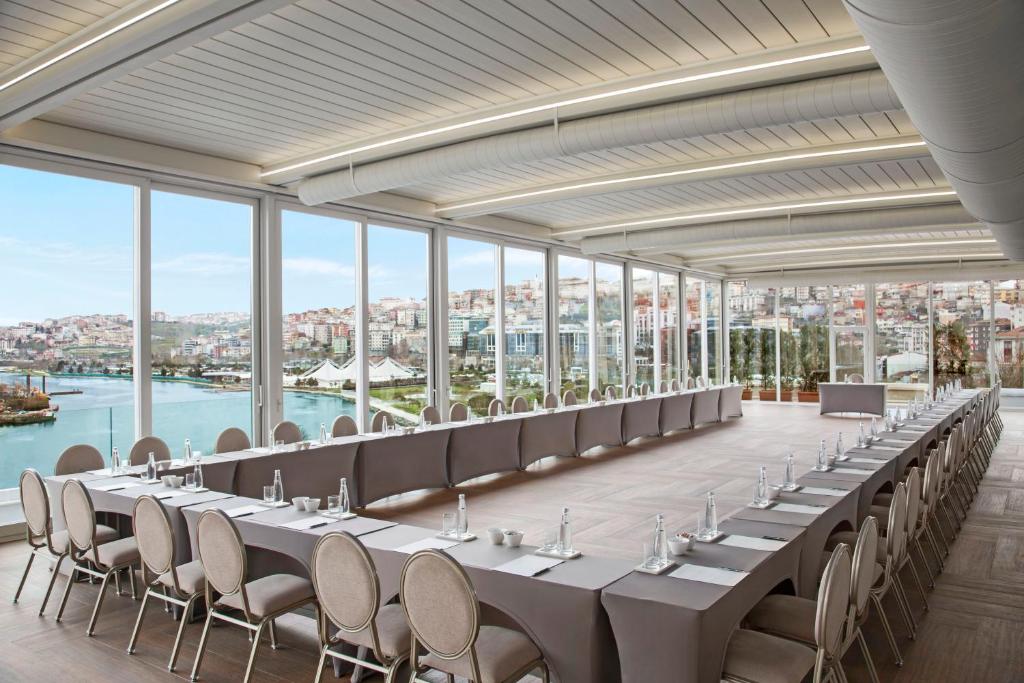 Lazzoni Hotel - a long row of tables and chairs in a room with windows at Lazzoni Hotel in Istanbul