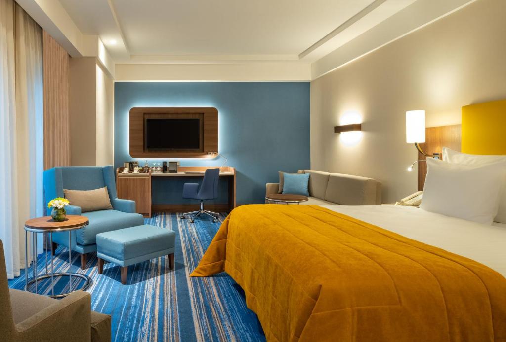 Mövenpick Hotel Istanbul Asia Airport - a hotel room with a bed and a chair and a tv at Mövenpick Hotel Istanbul Asia Airport in Istanbul