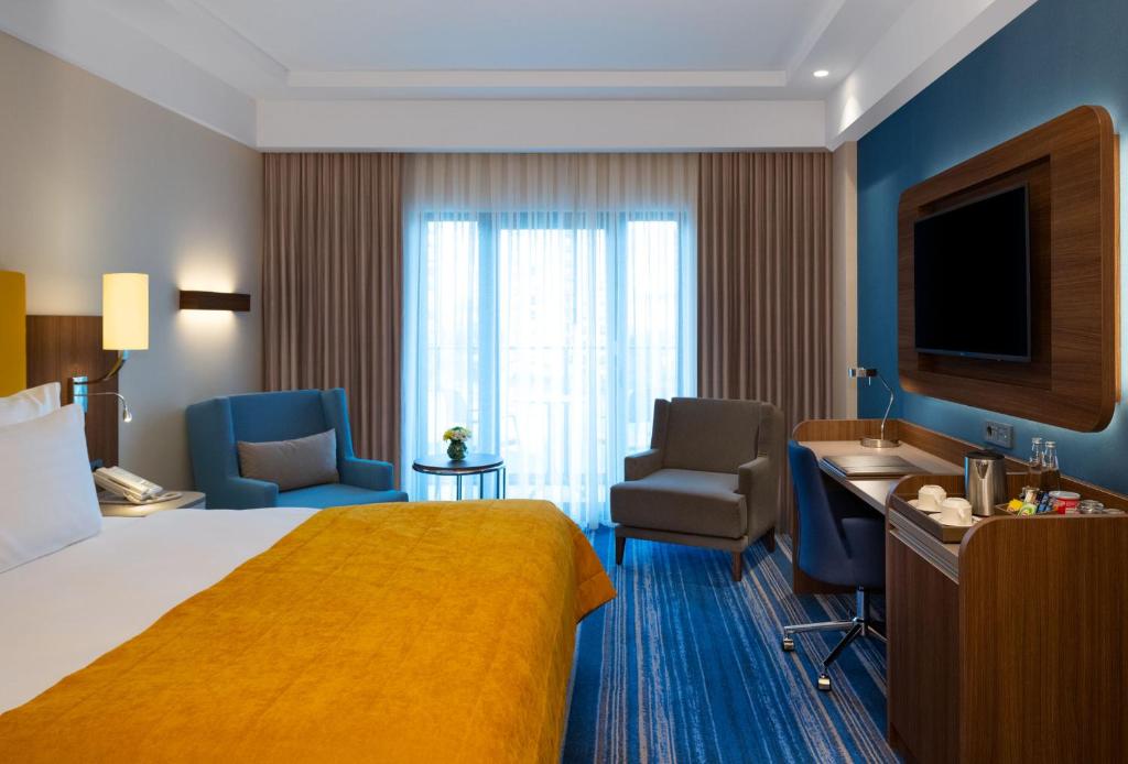 Mövenpick Hotel Istanbul Asia Airport - a hotel room with a bed and chairs and a television at Mövenpick Hotel Istanbul Asia Airport in Istanbul