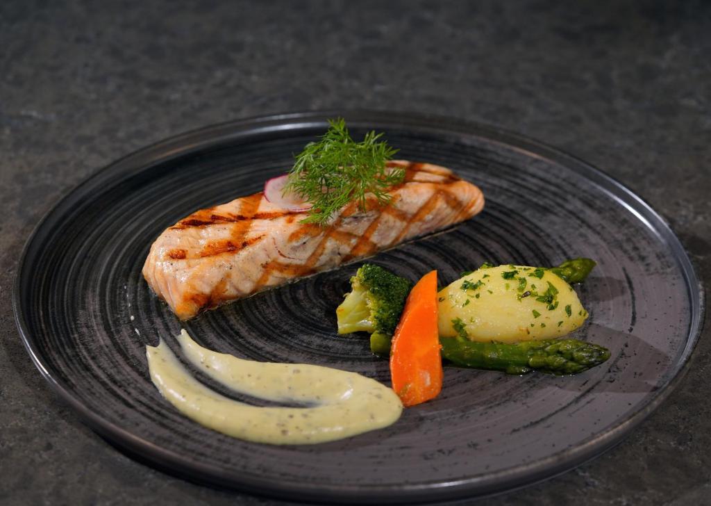Mövenpick Hotel Istanbul Asia Airport - a black plate of food with fish and vegetables at Mövenpick Hotel Istanbul Asia Airport in Istanbul