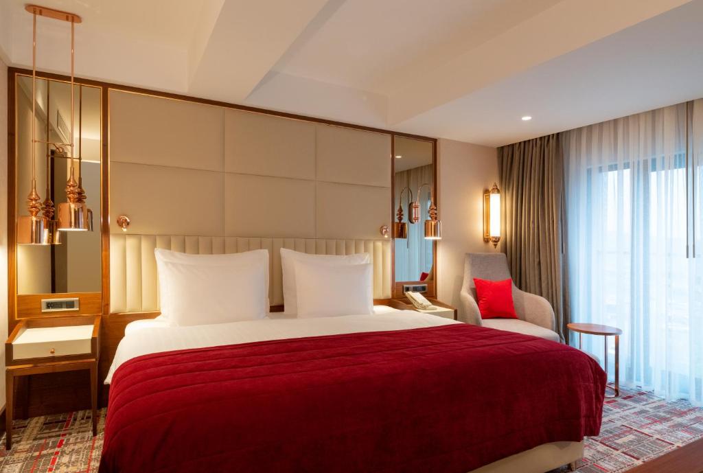 Mövenpick Hotel Istanbul Asia Airport - a hotel room with a large bed and a chair at Mövenpick Hotel Istanbul Asia Airport in Istanbul