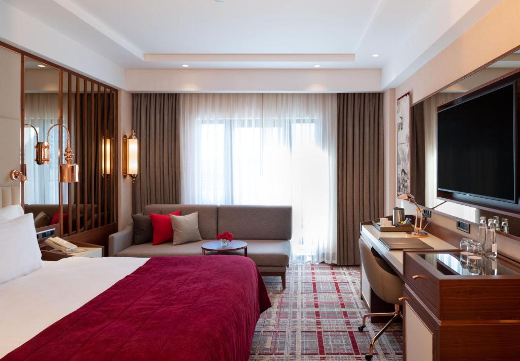 Mövenpick Hotel Istanbul Asia Airport - a hotel room with a bed and a couch and a television at Mövenpick Hotel Istanbul Asia Airport in Istanbul