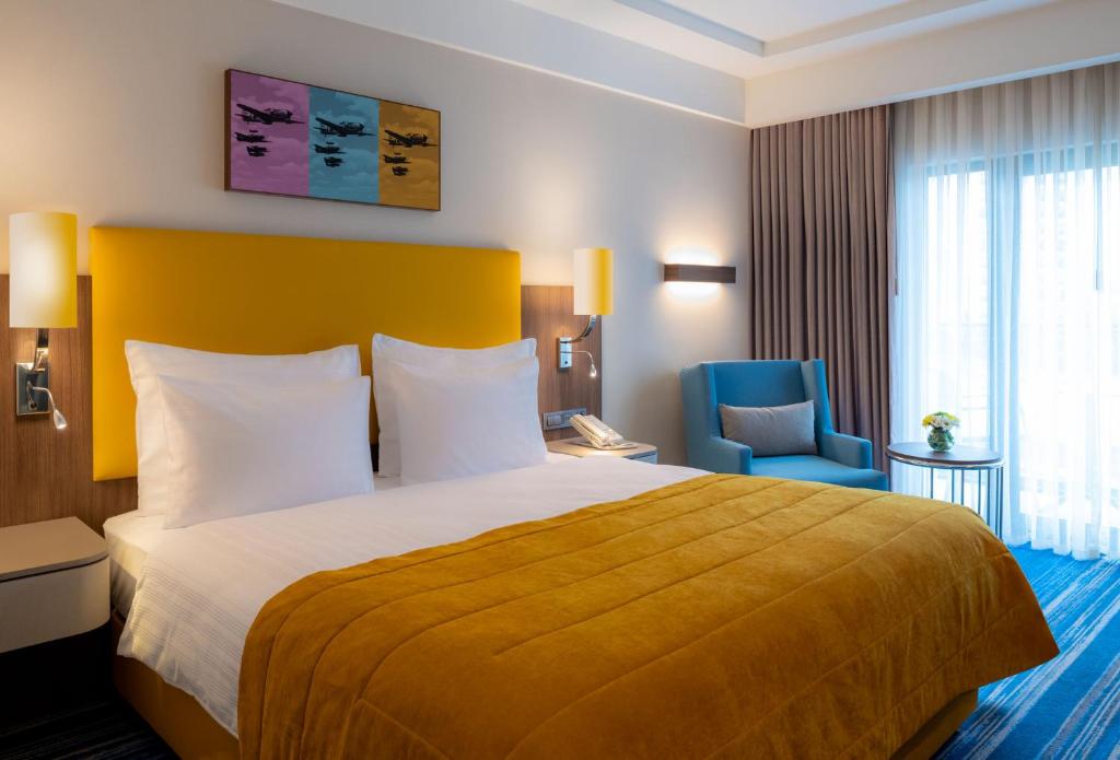 Mövenpick Hotel Istanbul Asia Airport - a hotel room with a bed and a blue chair at Mövenpick Hotel Istanbul Asia Airport in Istanbul