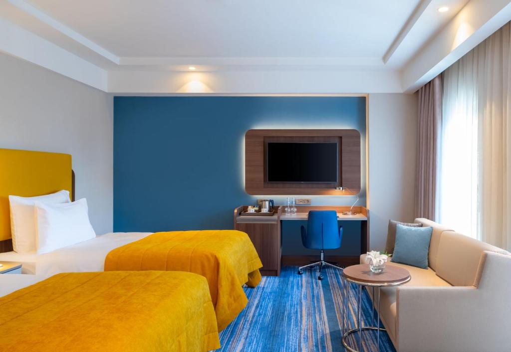 Mövenpick Hotel Istanbul Asia Airport - a hotel room with two beds and a flat screen tv at Mövenpick Hotel Istanbul Asia Airport in Istanbul