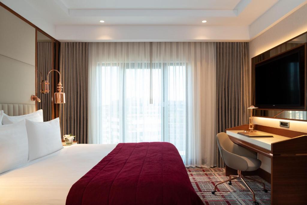 Mövenpick Hotel Istanbul Asia Airport - a hotel room with a bed and a desk and a television at Mövenpick Hotel Istanbul Asia Airport in Istanbul