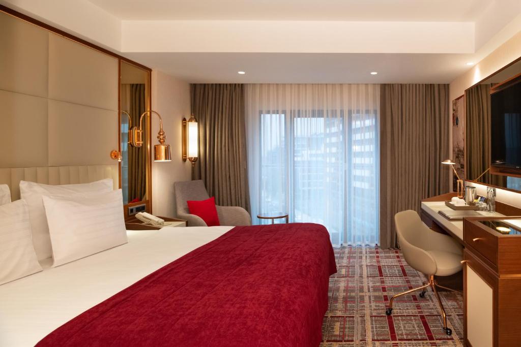Mövenpick Hotel Istanbul Asia Airport - a hotel room with a large bed and a desk at Mövenpick Hotel Istanbul Asia Airport in Istanbul
