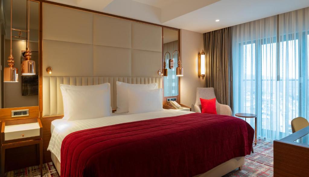 Mövenpick Hotel Istanbul Asia Airport - a hotel room with a bed with a red blanket at Mövenpick Hotel Istanbul Asia Airport in Istanbul