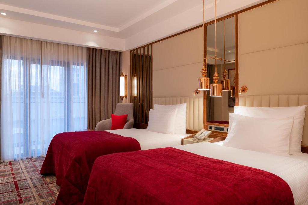 Mövenpick Hotel Istanbul Asia Airport - a hotel room with two beds with red sheets at Mövenpick Hotel Istanbul Asia Airport in Istanbul