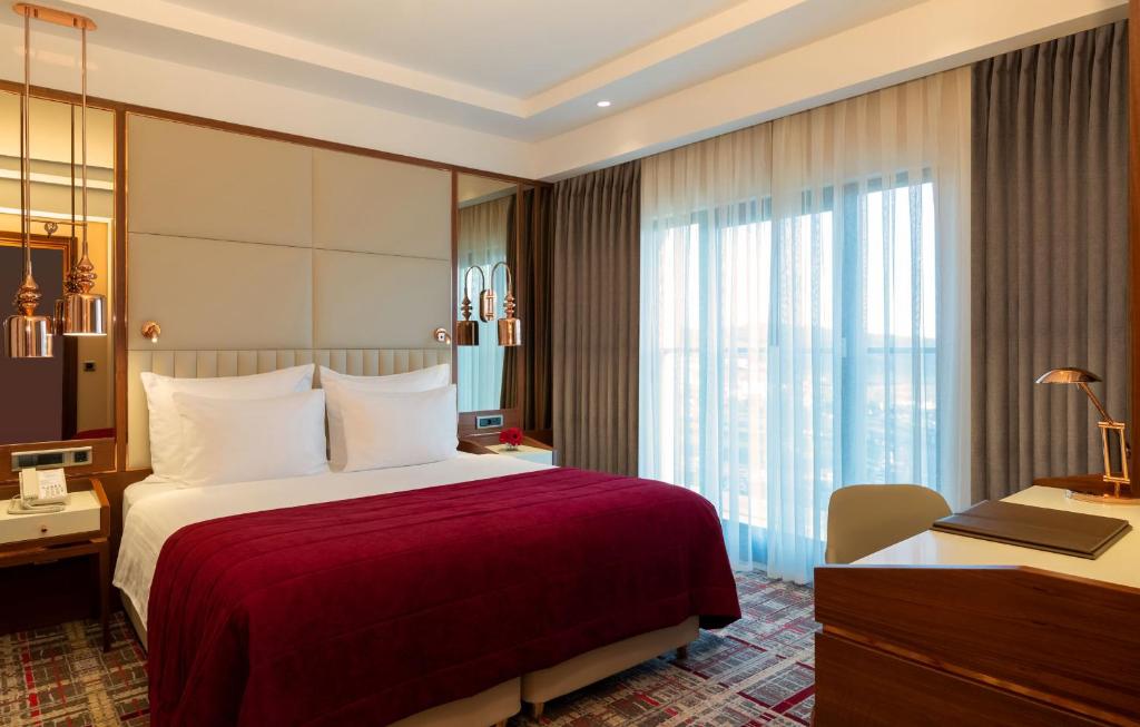 Mövenpick Hotel Istanbul Asia Airport - a hotel room with a large bed and a desk at Mövenpick Hotel Istanbul Asia Airport in Istanbul
