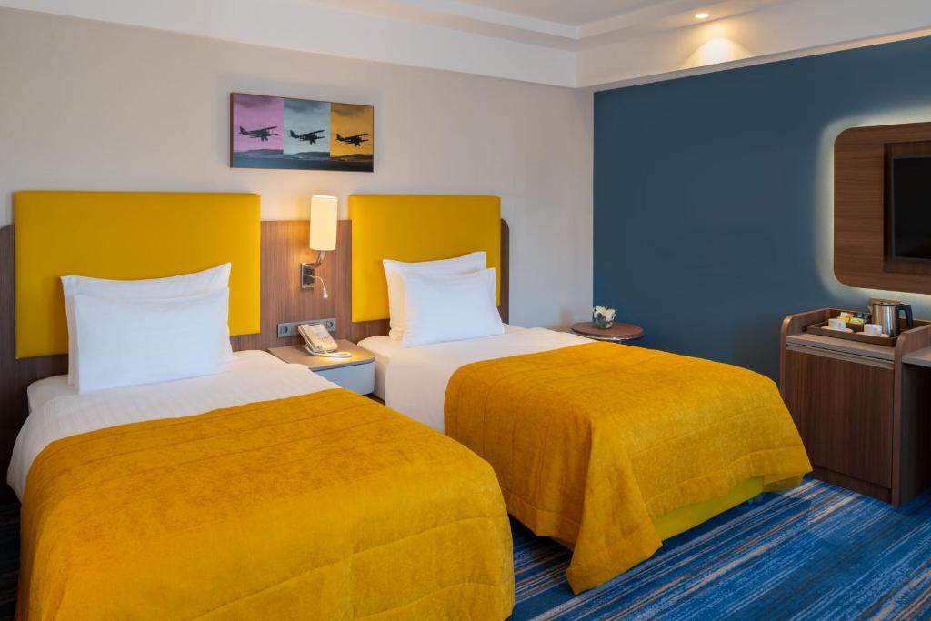 Mövenpick Hotel Istanbul Asia Airport - a hotel room with two beds and a tv at Mövenpick Hotel Istanbul Asia Airport in Istanbul