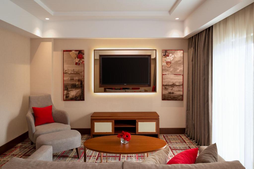 Mövenpick Hotel Istanbul Asia Airport - a living room with a tv and a couch and a table at Mövenpick Hotel Istanbul Asia Airport in Istanbul