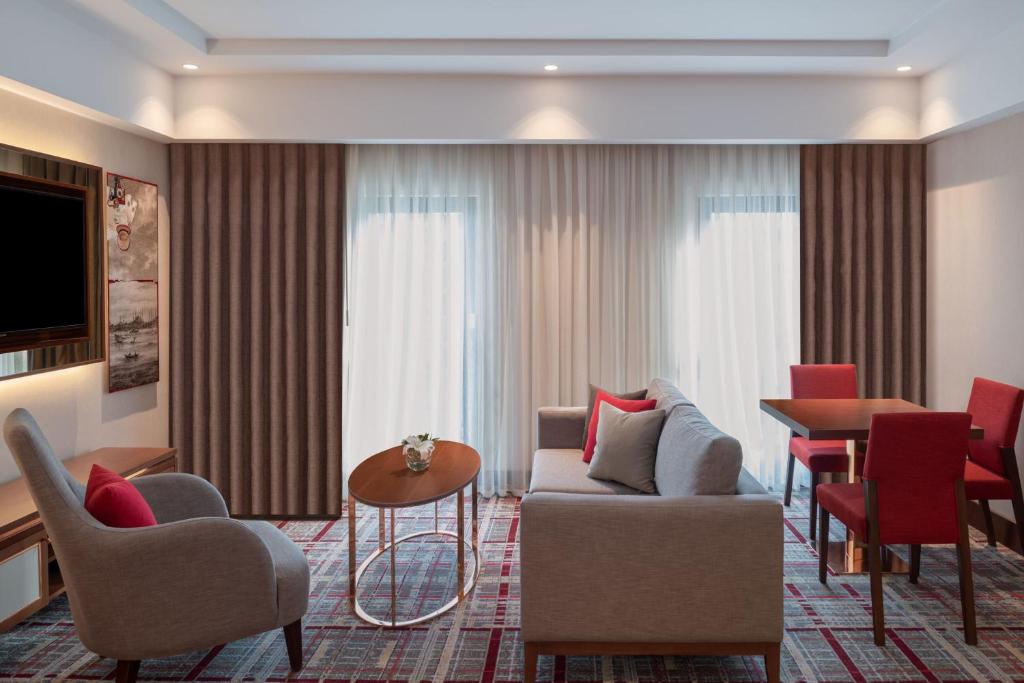 Mövenpick Hotel Istanbul Asia Airport - a hotel room with a couch and chairs and a table at Mövenpick Hotel Istanbul Asia Airport in Istanbul