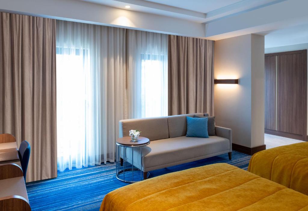 Mövenpick Hotel Istanbul Asia Airport - a hotel room with a bed and a couch and a table at Mövenpick Hotel Istanbul Asia Airport in Istanbul