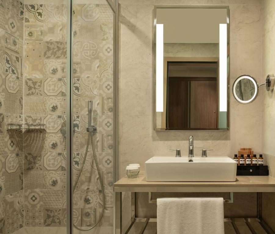 Mövenpick Hotel Istanbul Asia Airport - a bathroom with a sink and a shower with a mirror at Mövenpick Hotel Istanbul Asia Airport in Istanbul