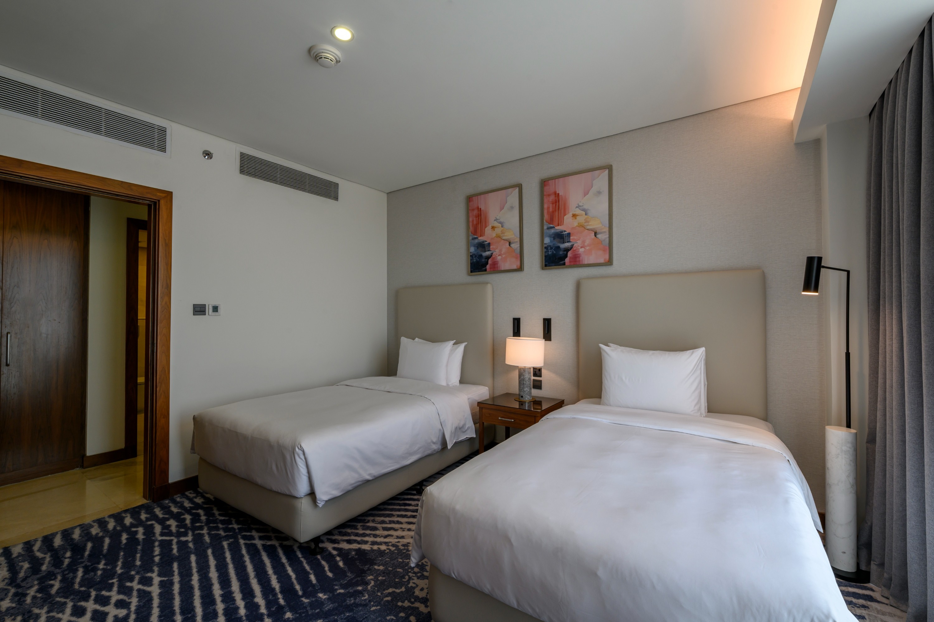 DoubleTree Jeddah suite with two beds, modern decor.