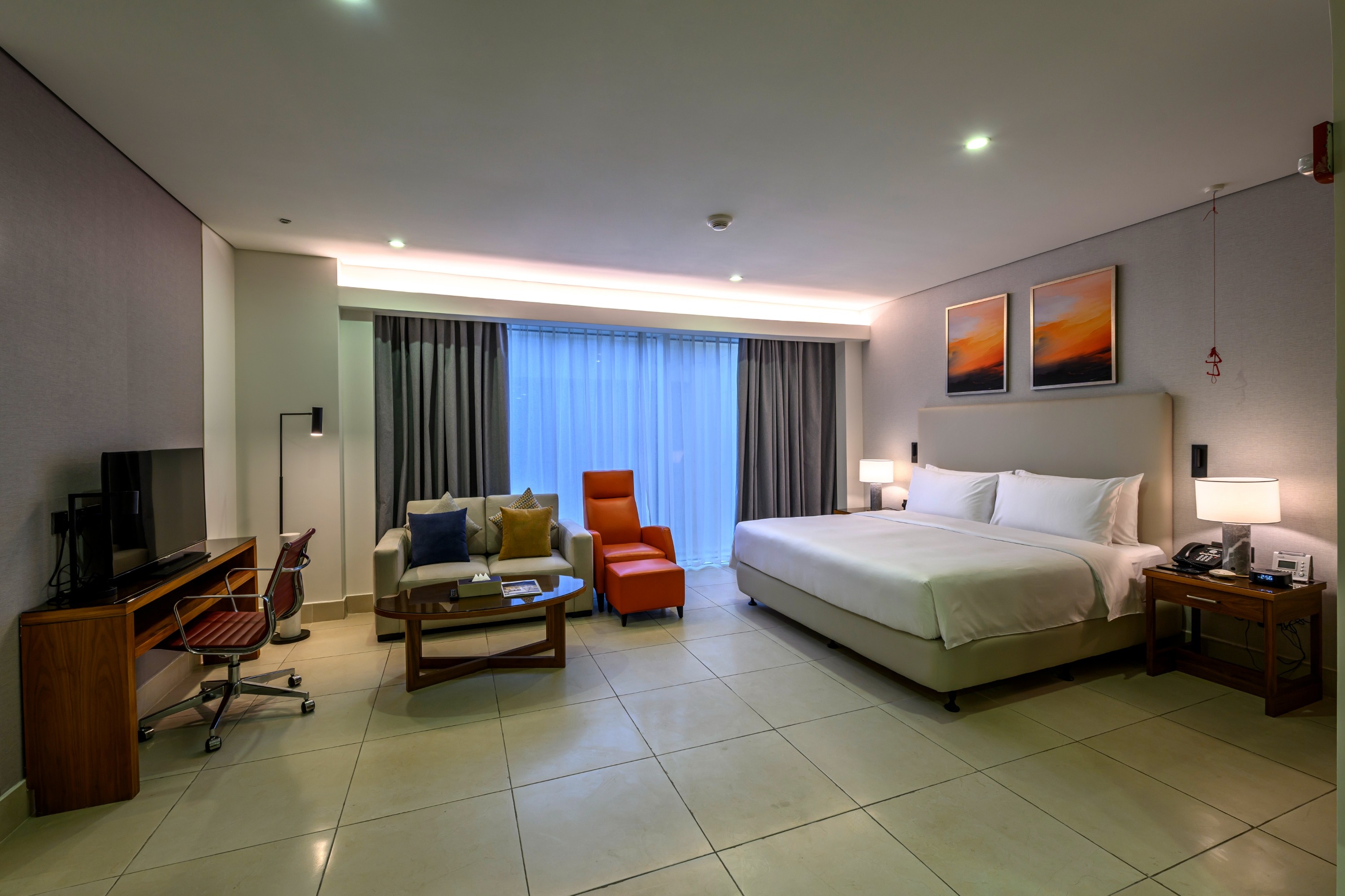 Spacious guest room with bed, sofa, and desk in hotel.