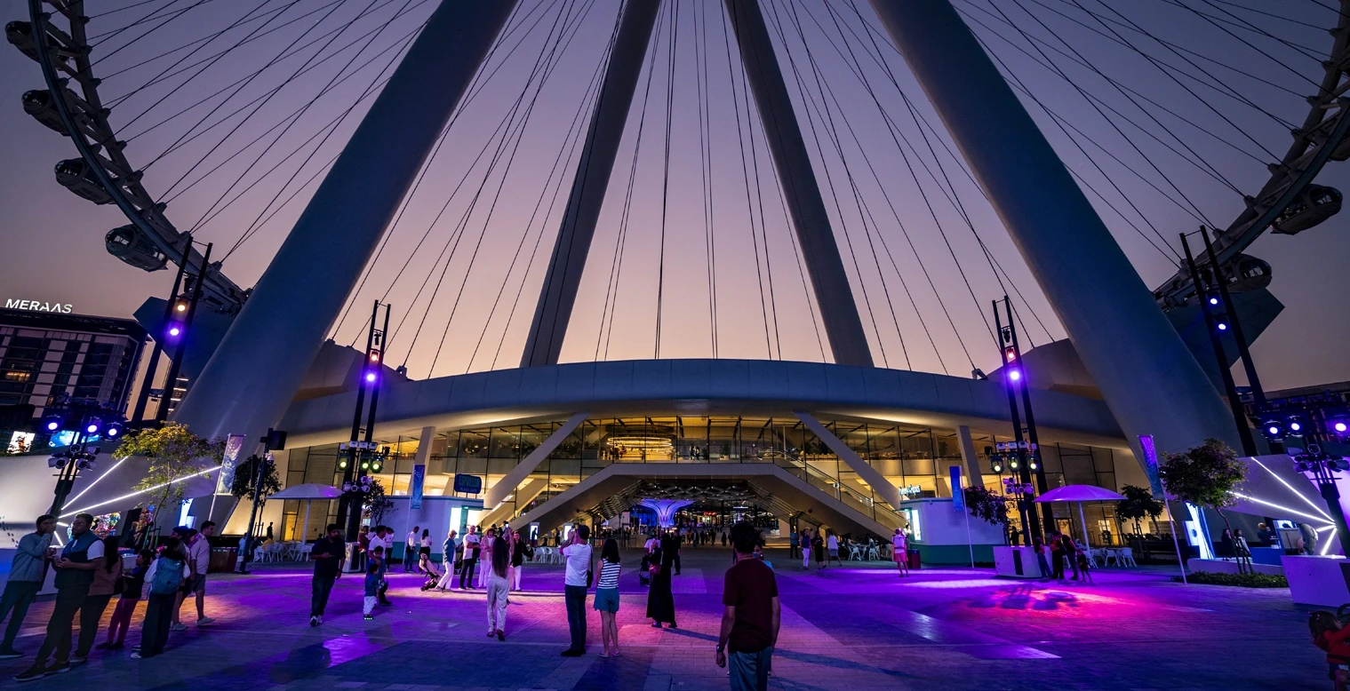 Ain Dubai venue exterior at sunset, vibrant lights, people gathering.