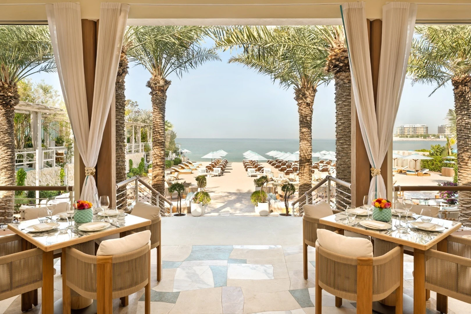 Nammos Dubai beachfront venue with elegant dining setup and palm trees.