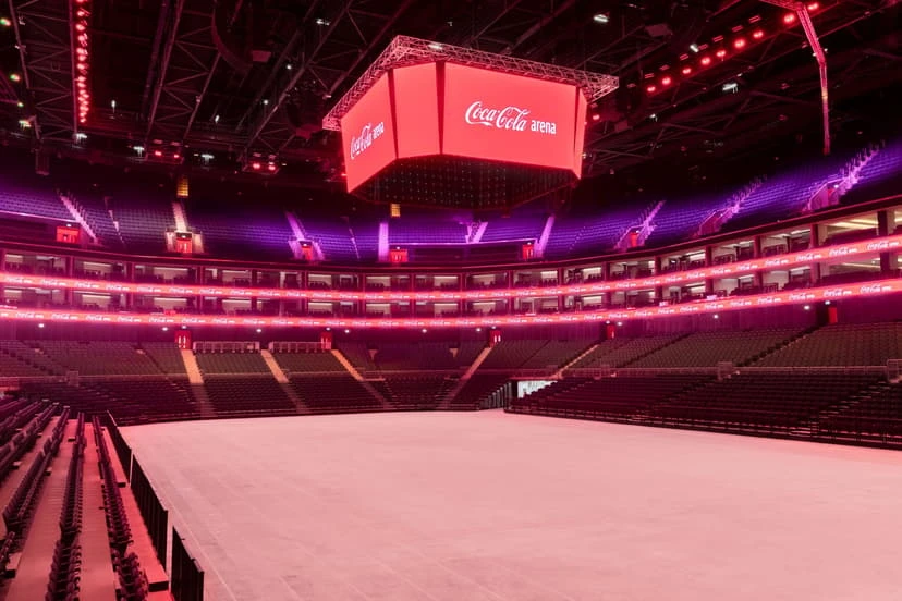Interior of Coca-Cola Arena in Dubai, empty seating, red lighting.
