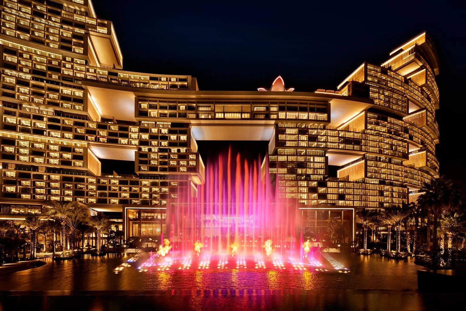 Illuminated Atlantis The Royal Dubai with vibrant fountain display at night.