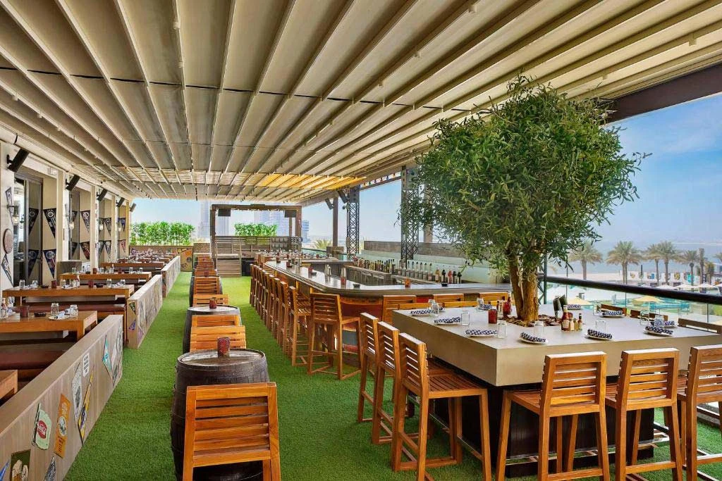 Outdoor dining area at Hilton Dubai Palm Jumeirah, overlooking the beach.