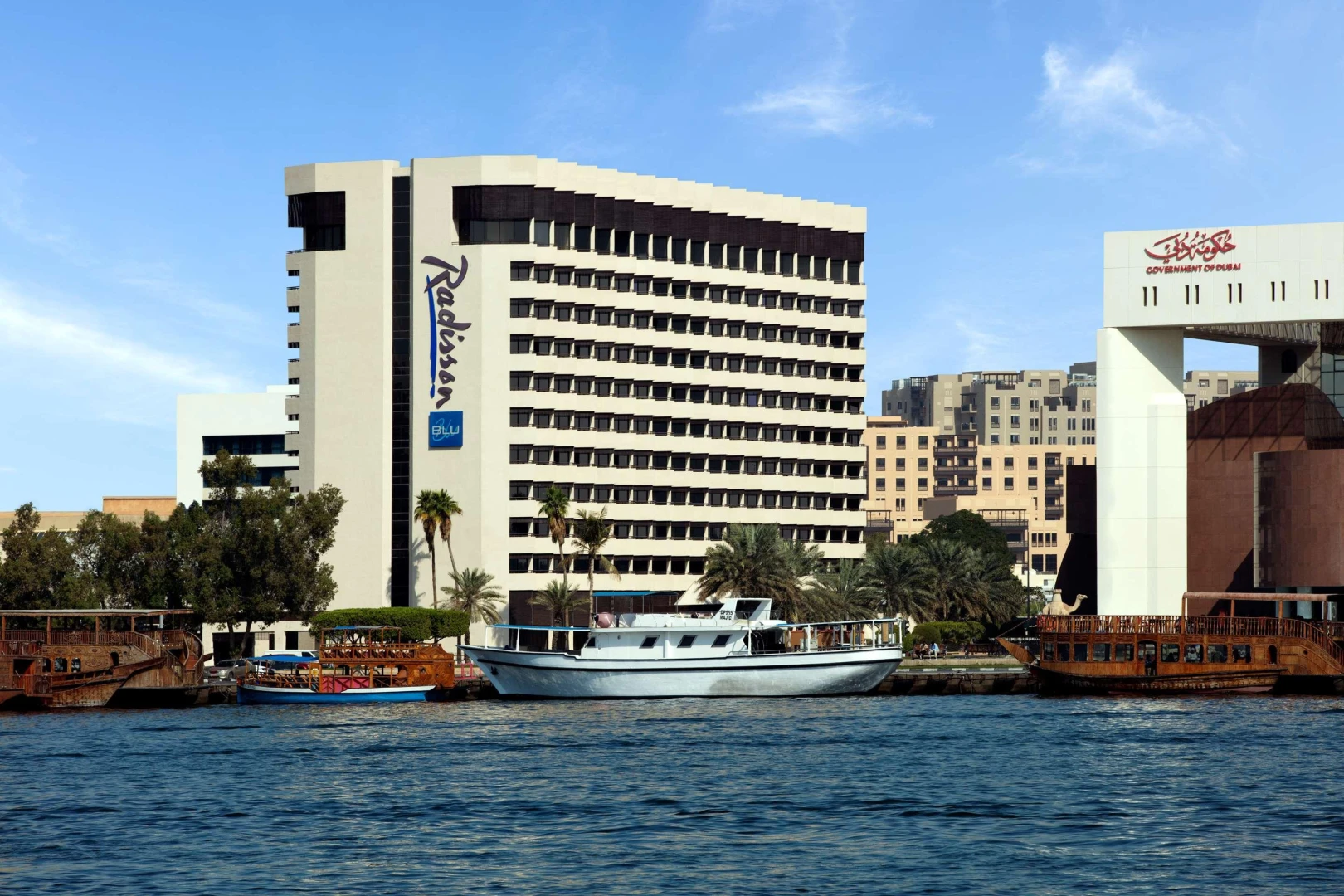 Radisson Blu Hotel, Dubai Deira Creek by waterfront, sunny day.