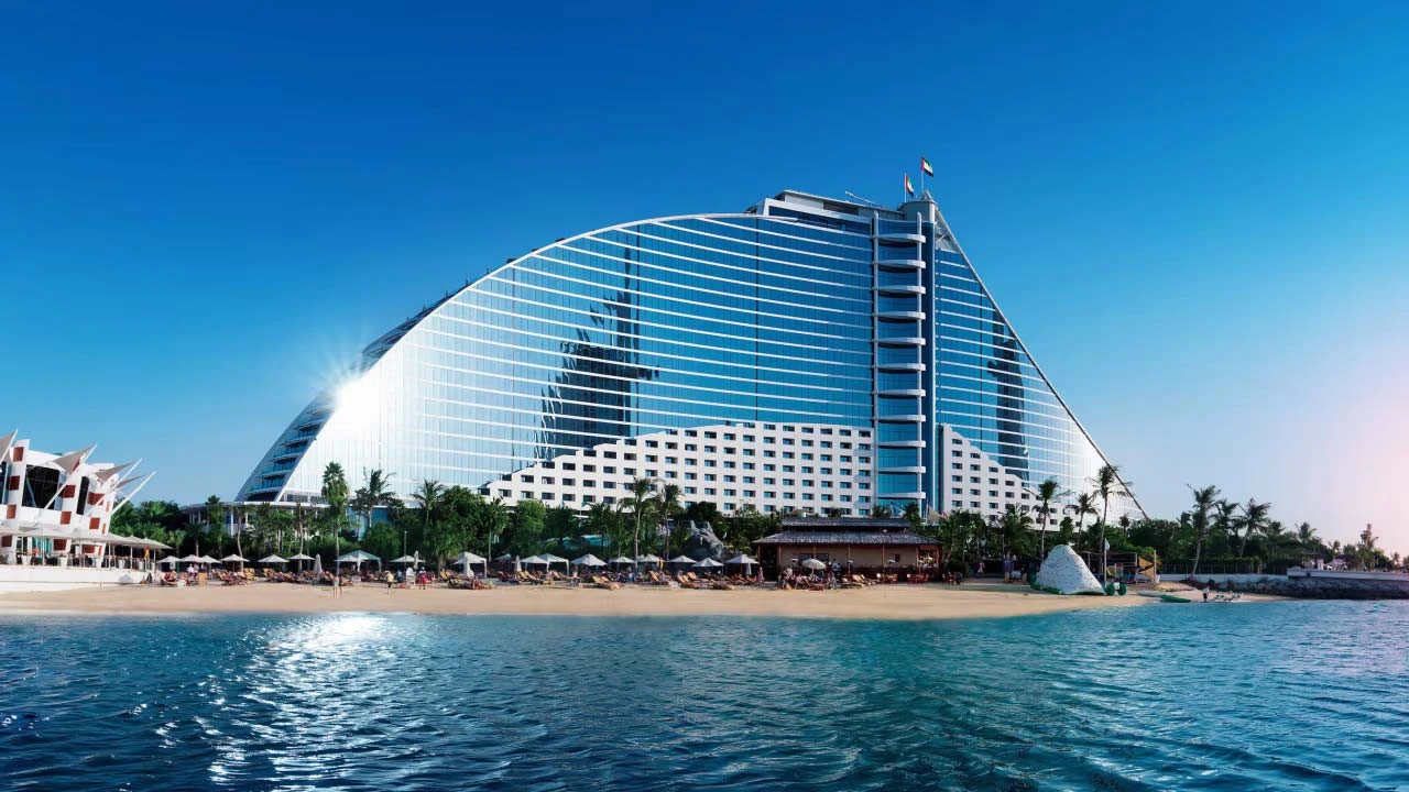 Jumeirah Beach Hotel's modern architecture against blue sky, Dubai waterfront.