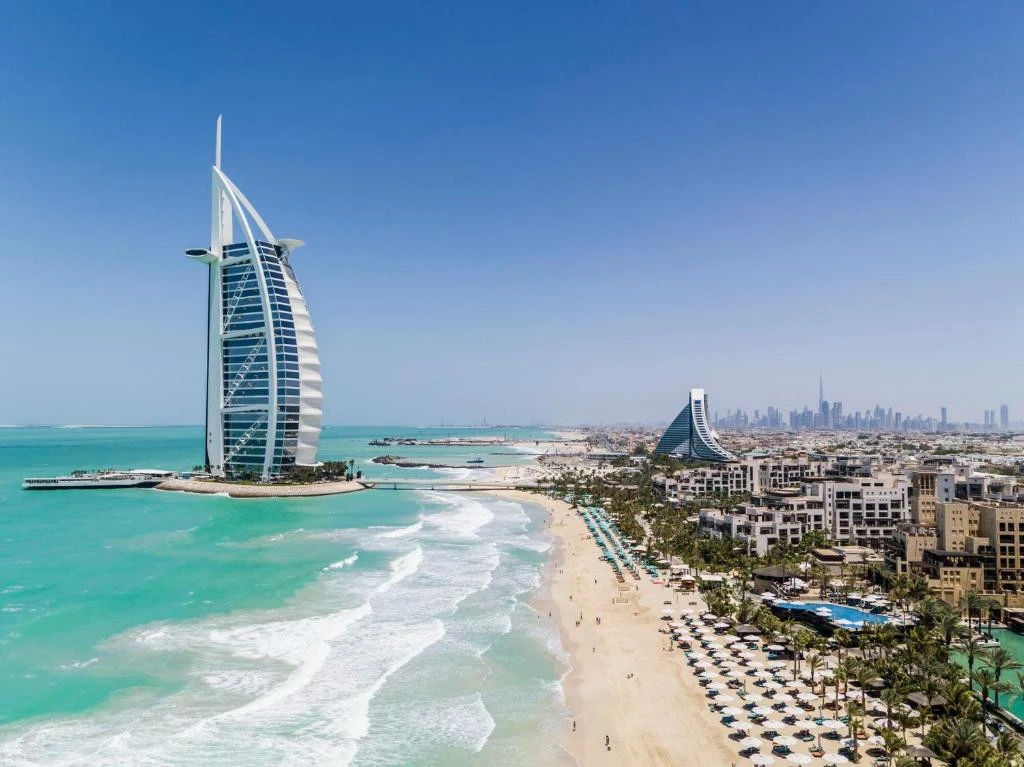Jumeirah Beach Hotel and coastline in Dubai, clear blue sky.