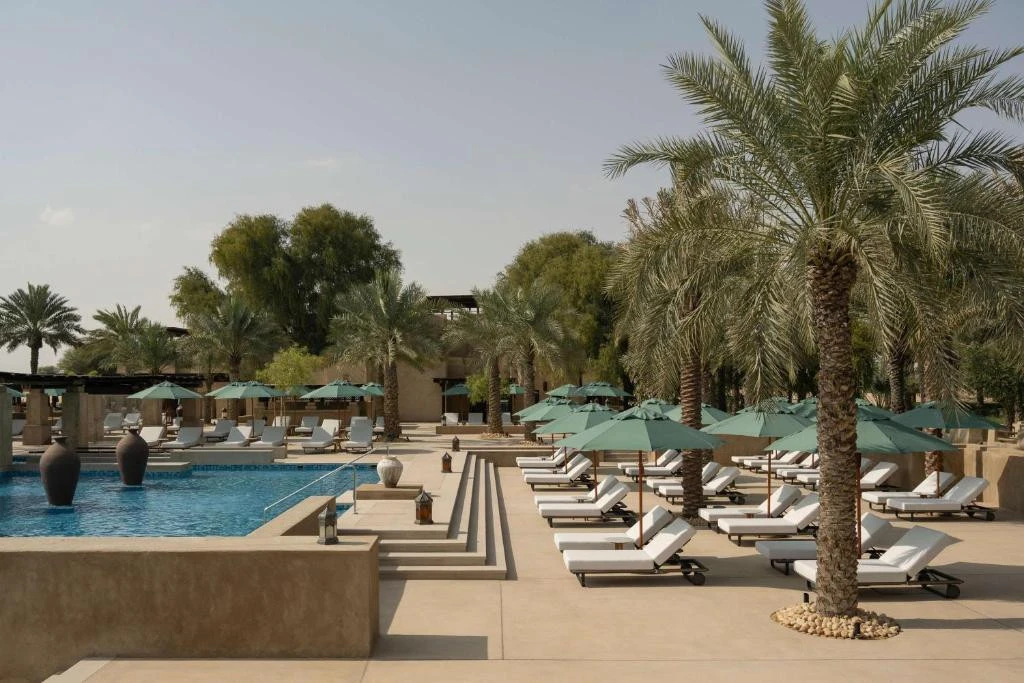 Poolside loungers and palm trees at Bab Al Shams, Dubai resort.
