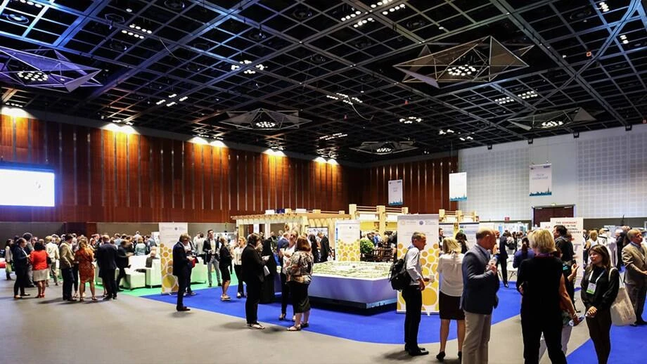 Crowded event at Dubai World Trade Centre, spacious hall, networking attendees.