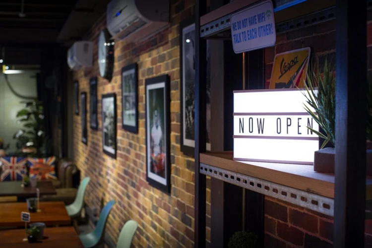 Warehouse Four Dubai interior with 'Now Open' sign and seating.