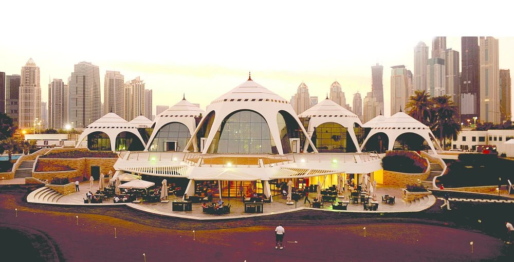 Emirates Golf Club clubhouse with Dubai skyline at sunset.