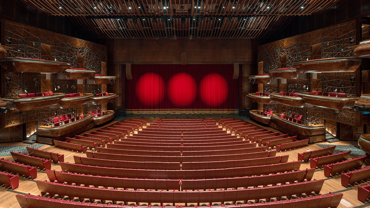 Elegant interior of Dubai Opera with red seats and stage curtains.