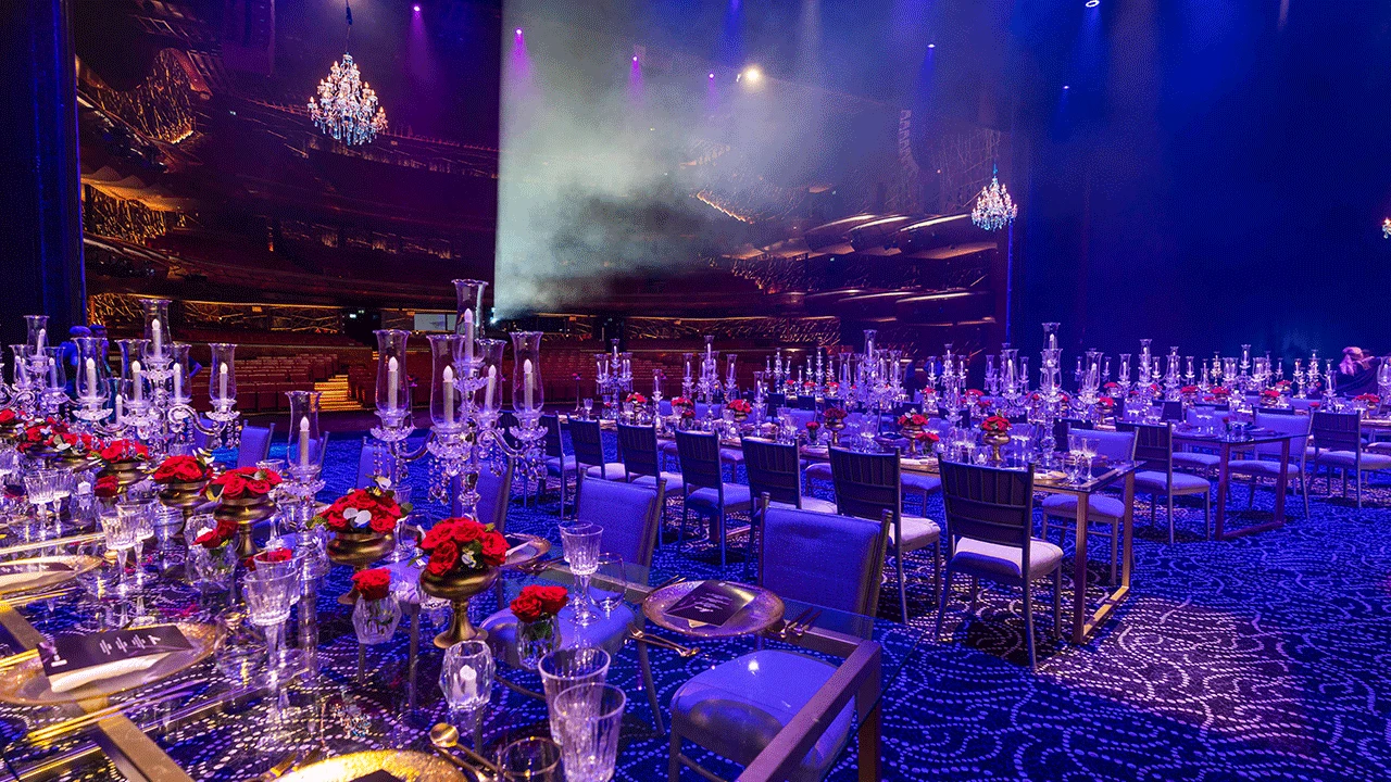 Elegant banquet setup at Dubai Opera with chandeliers and floral decor.