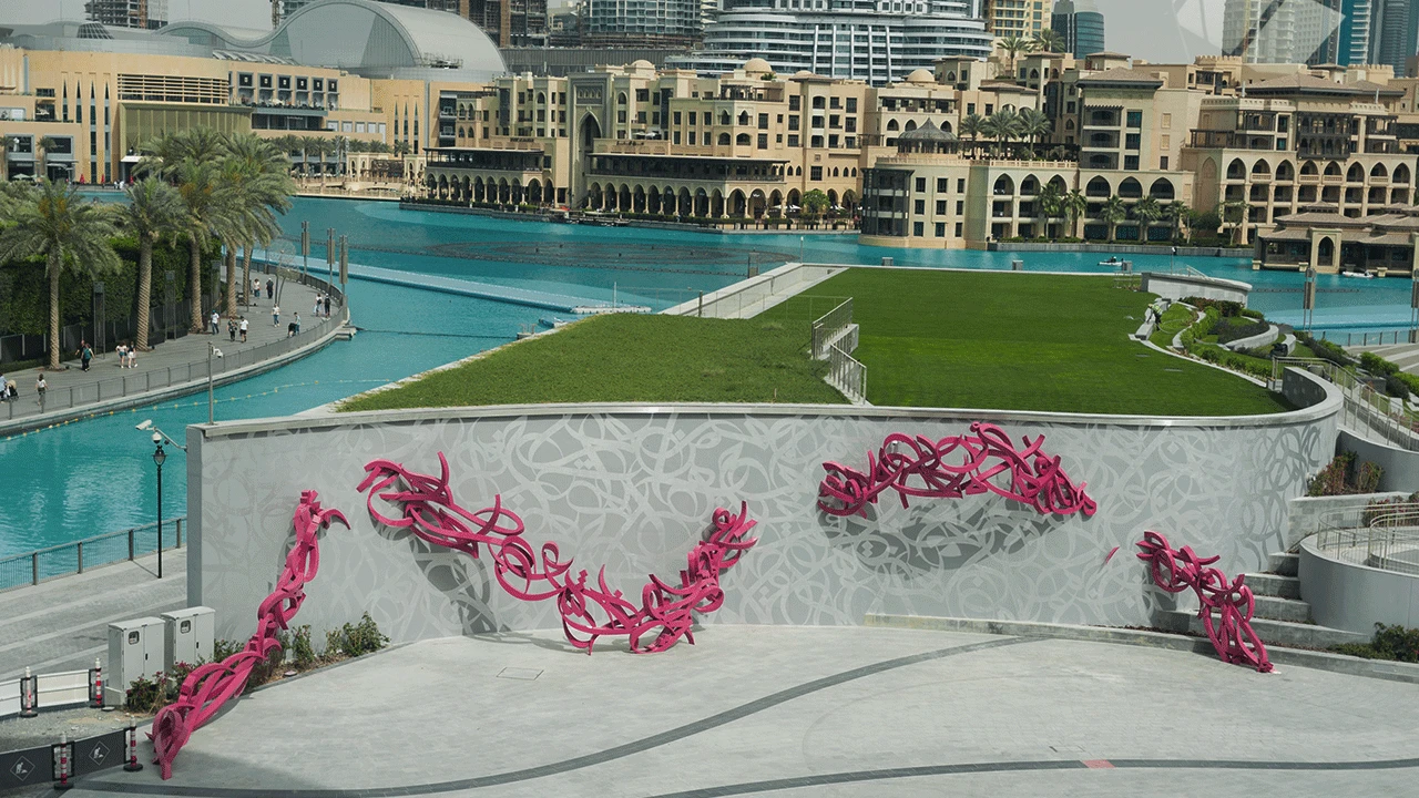 Dubai Opera exterior with pink sculptures and waterfront view.