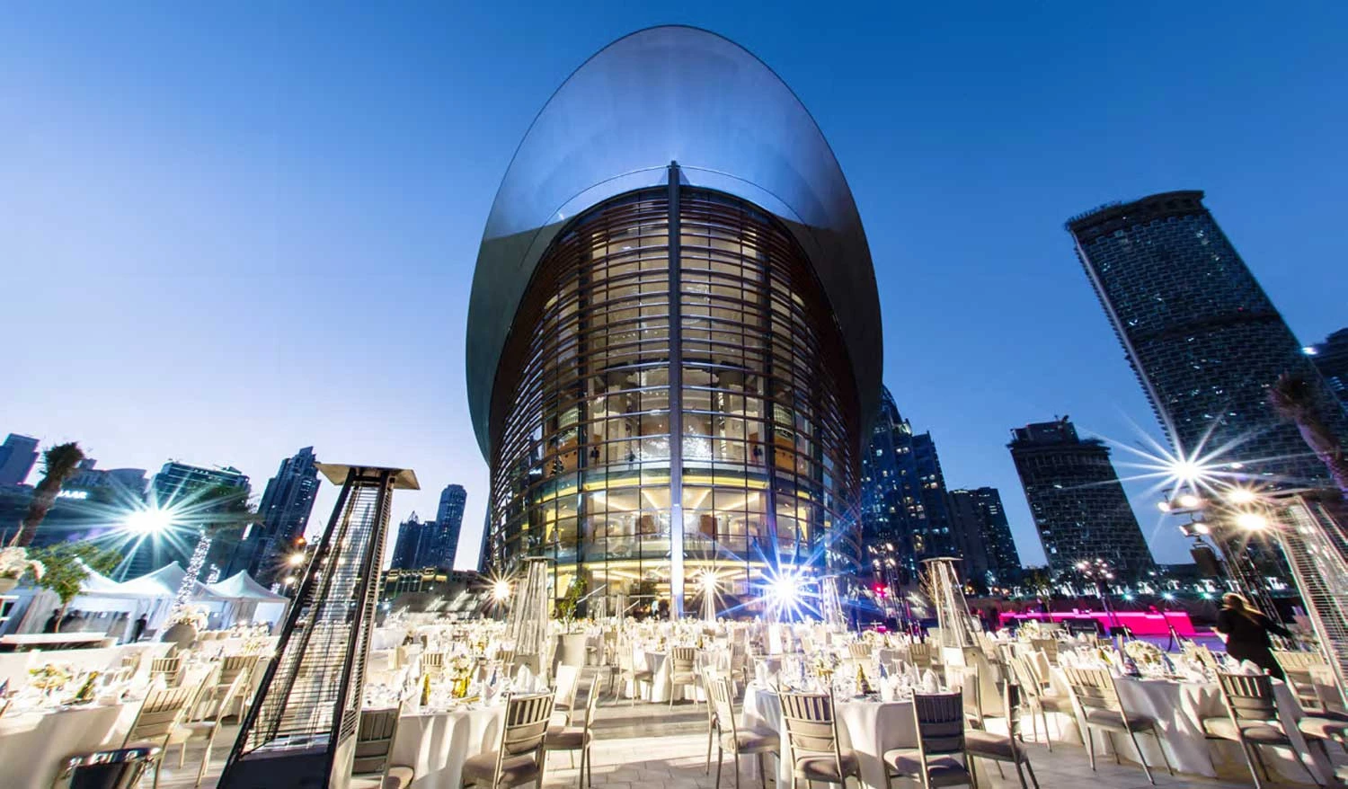 Dubai Opera illuminated at night with outdoor dining setup.