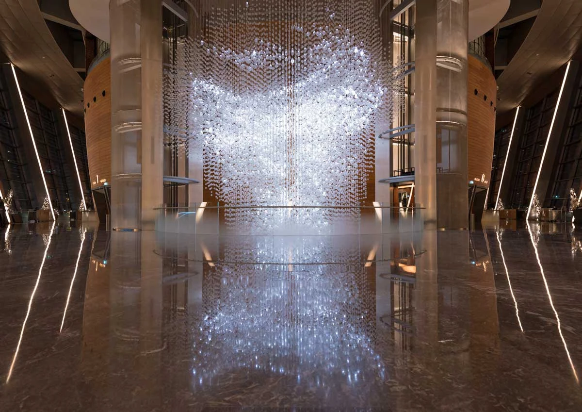 Elegant chandelier in Dubai Opera's modern, reflective interior.