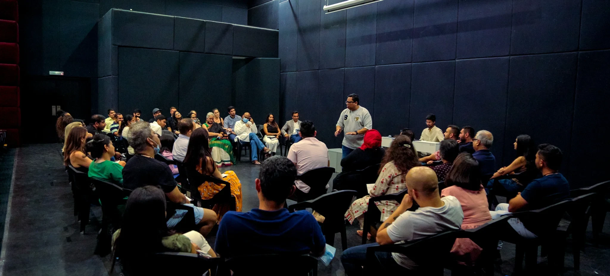 Audience gathered for event at The Junction Dubai, dark theater setting.