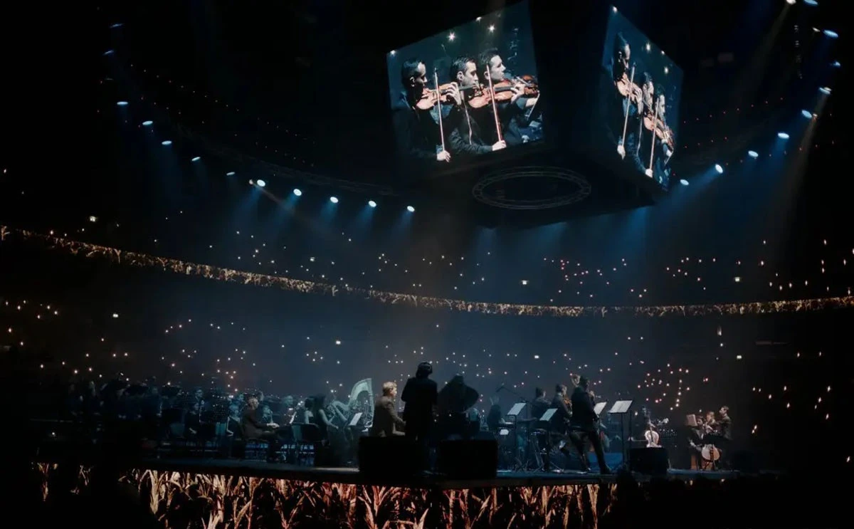 Orchestra performing at Coca-Cola Arena, Dubai, with illuminated audience.