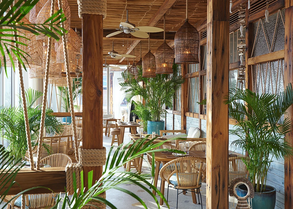 Tropical-themed interior of Koko Bay restaurant in Dubai with wooden decor.