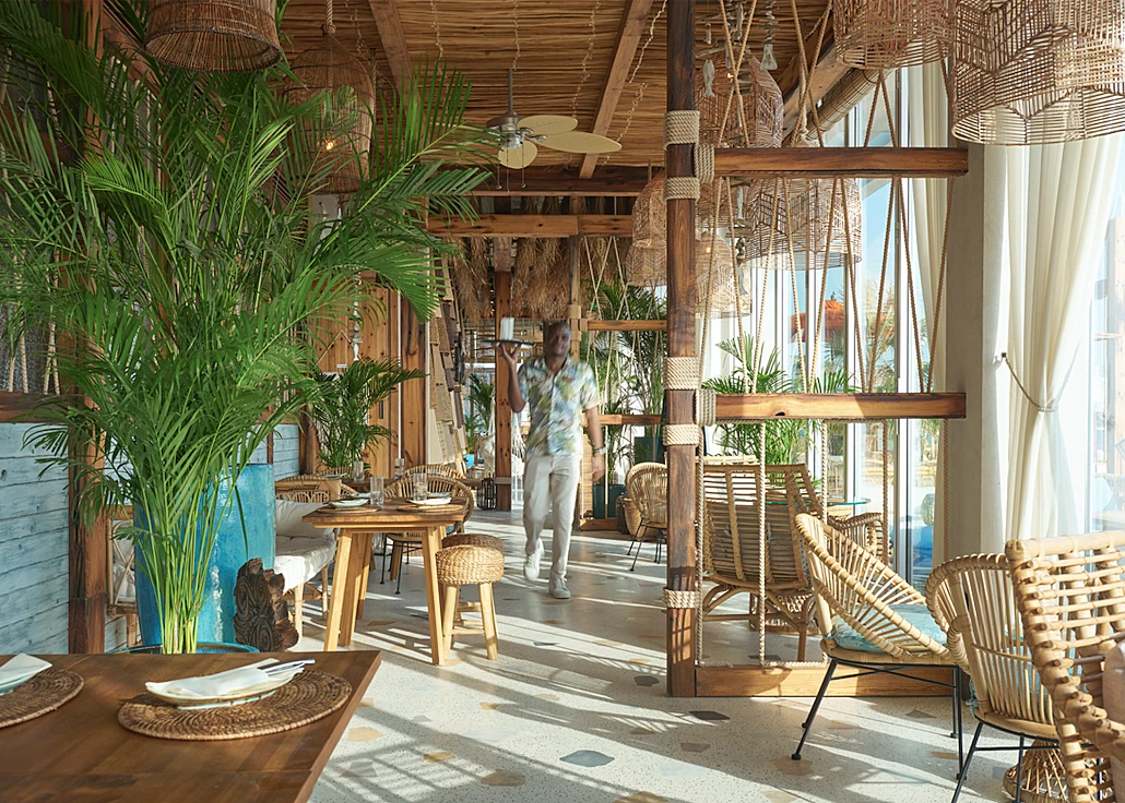 Tropical interior of Koko Bay restaurant in Dubai with wooden decor.