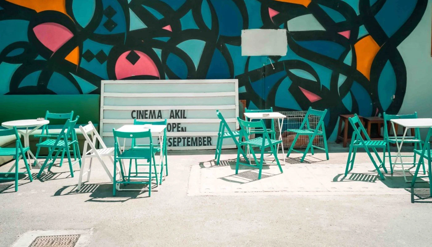 Outdoor seating at Cinema Akil, Dubai, with colorful mural background.