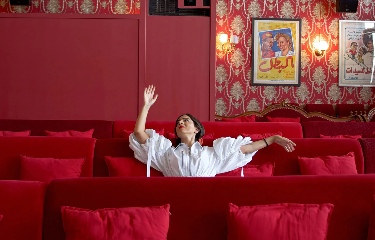 Person in white dress sitting in Cinema Akil, Dubai.