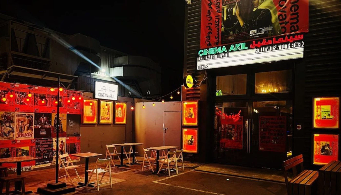 Cinema Akil entrance with outdoor seating, illuminated at night, Dubai.