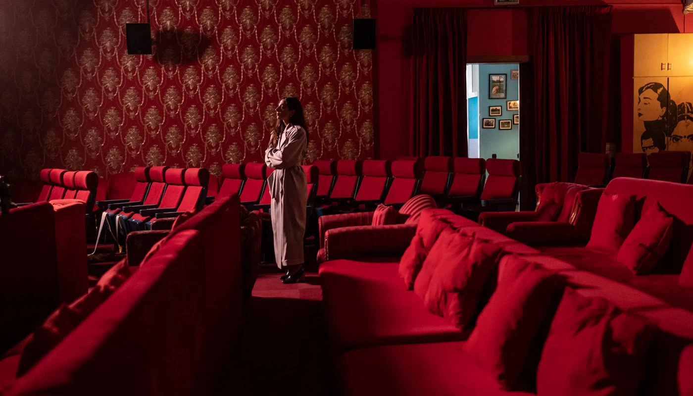 Cinema Akil Dubai, red seating, patterned walls, person standing.