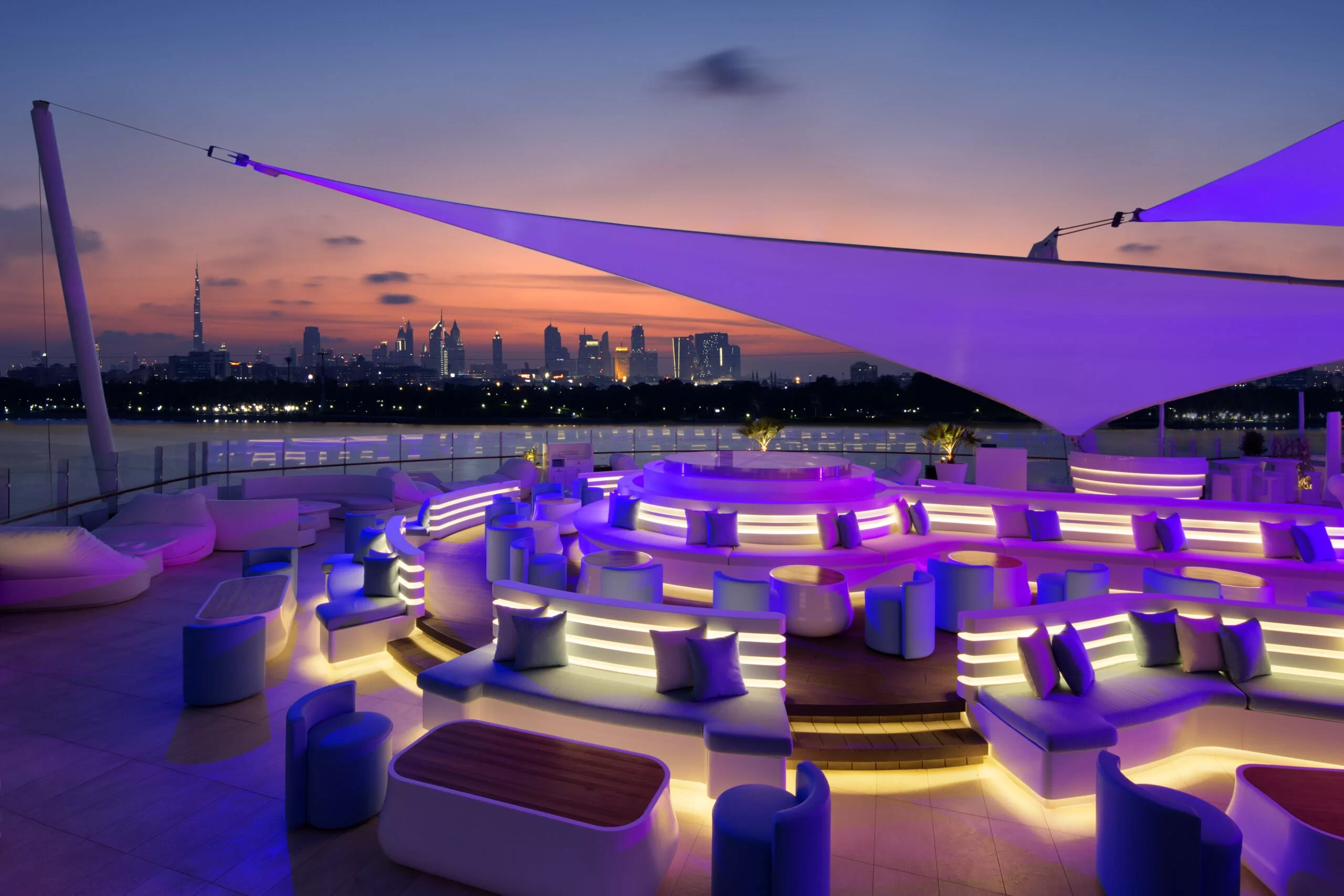 Dubai Creek Golf & Yacht Club terrace at sunset with city skyline.