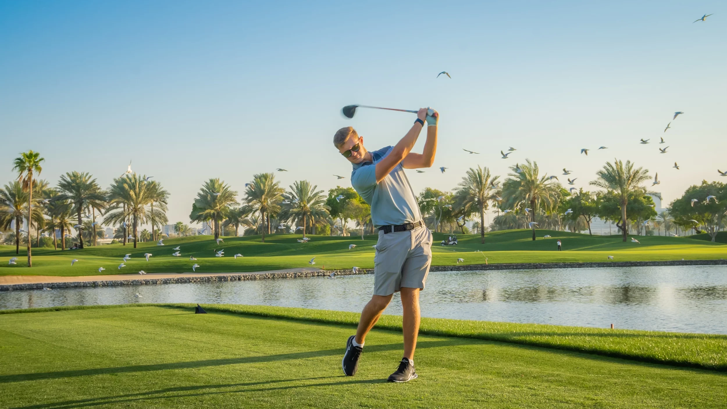 Golfer swinging at Dubai Creek Golf & Yacht Club, Dubai.